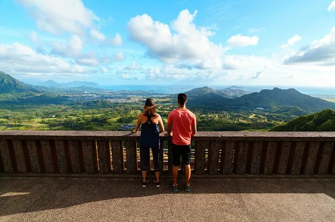 Dos visitantes junto al muro de piedra del Nuuanu Pali Lookout, sobre el lado de barlovento de Oahu