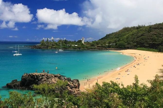 Der sandige Halbmond der Waimea Bay und das blaue Wasser, vom Hang darüber gesehen